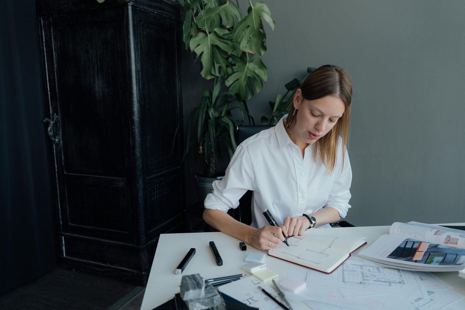 A young female architect working on floor plans at home, blending creativity and professionalism.