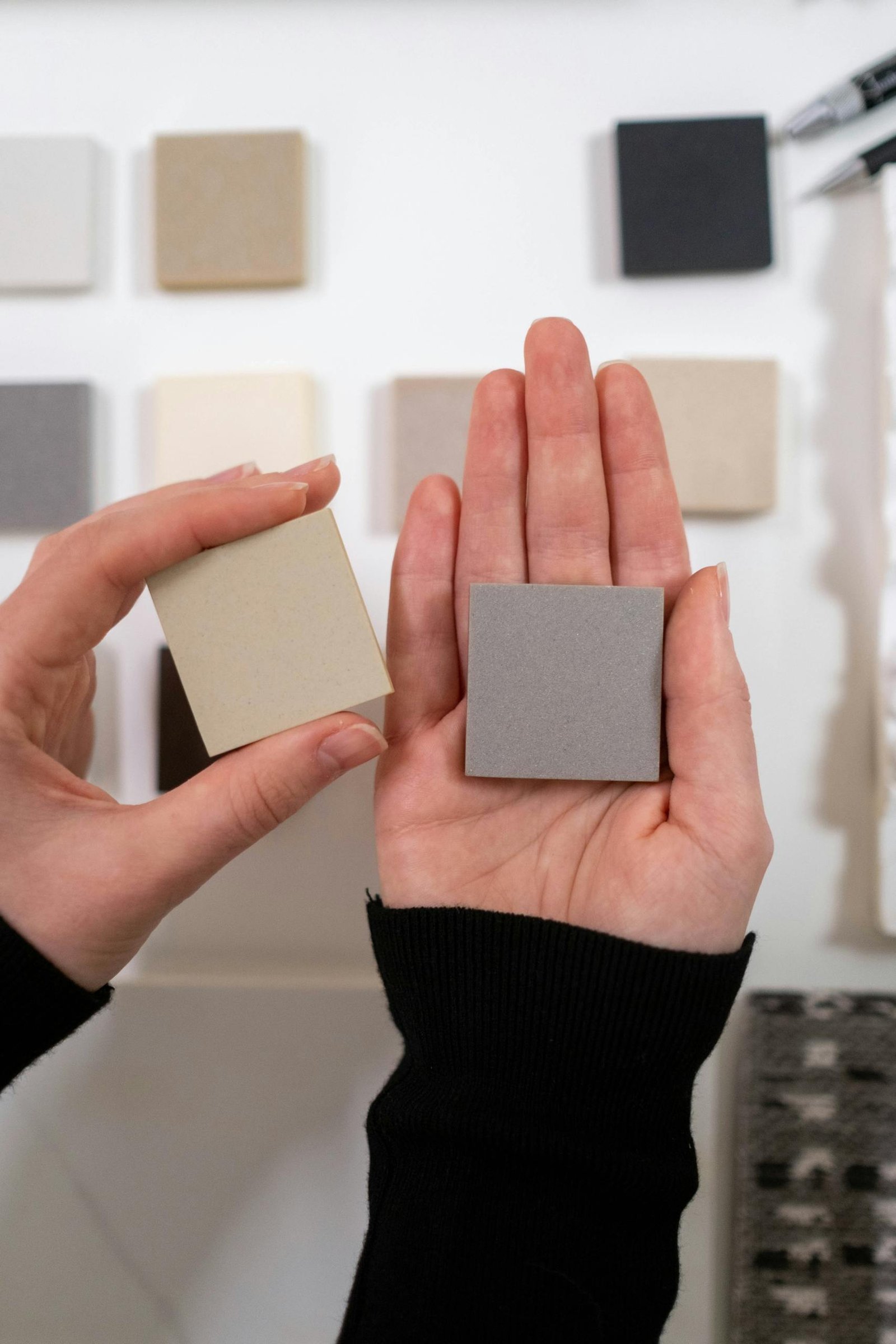 Close-up of hands holding color swatches in a design setting, showcasing selection and creativity.