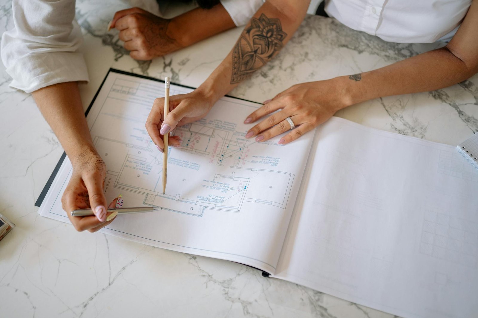 Two women collaborating on architectural blueprints, emphasizing teamwork and design.